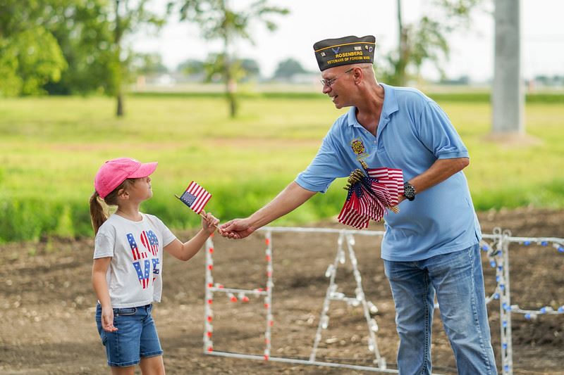 Veteran Handing a Flag to a Girl