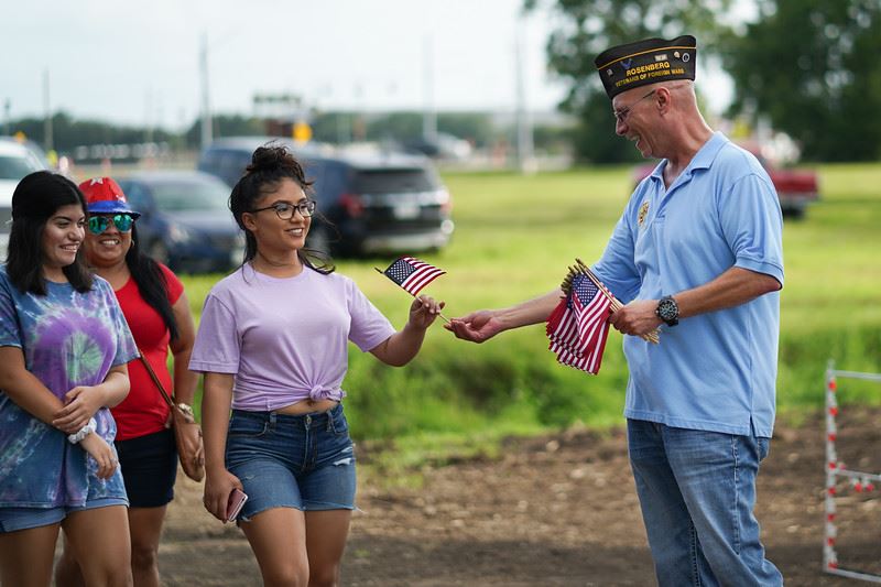 Veteran Handing a Young Woman a Flag